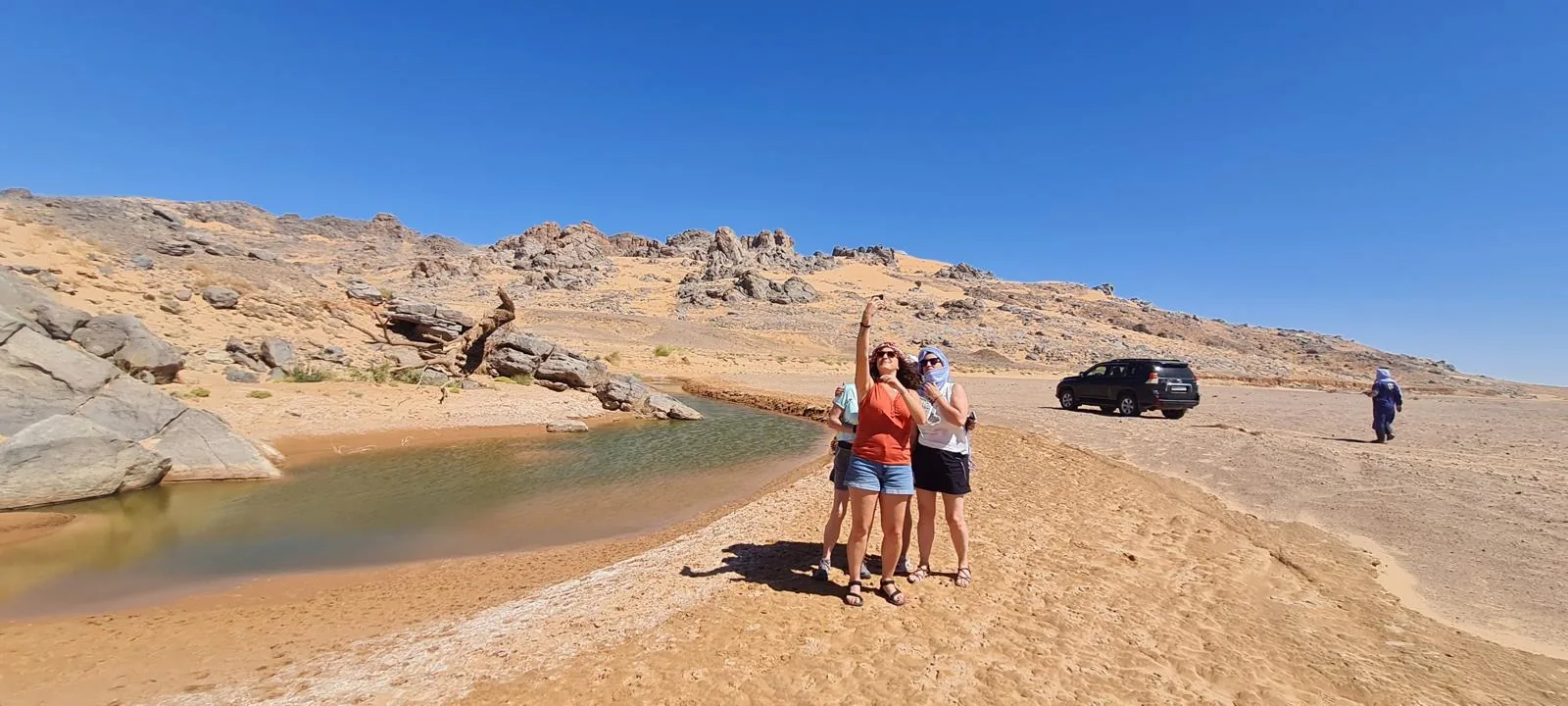 Grupo de viajeros junto a un 4x4 en una zona rocosa del desierto