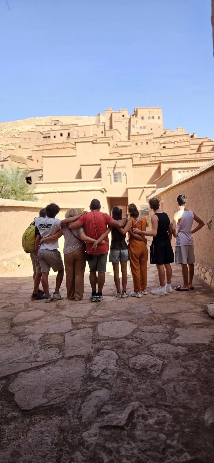 Grupo de viajeros abrazados frente a la kasbah de Ait Ben Haddou