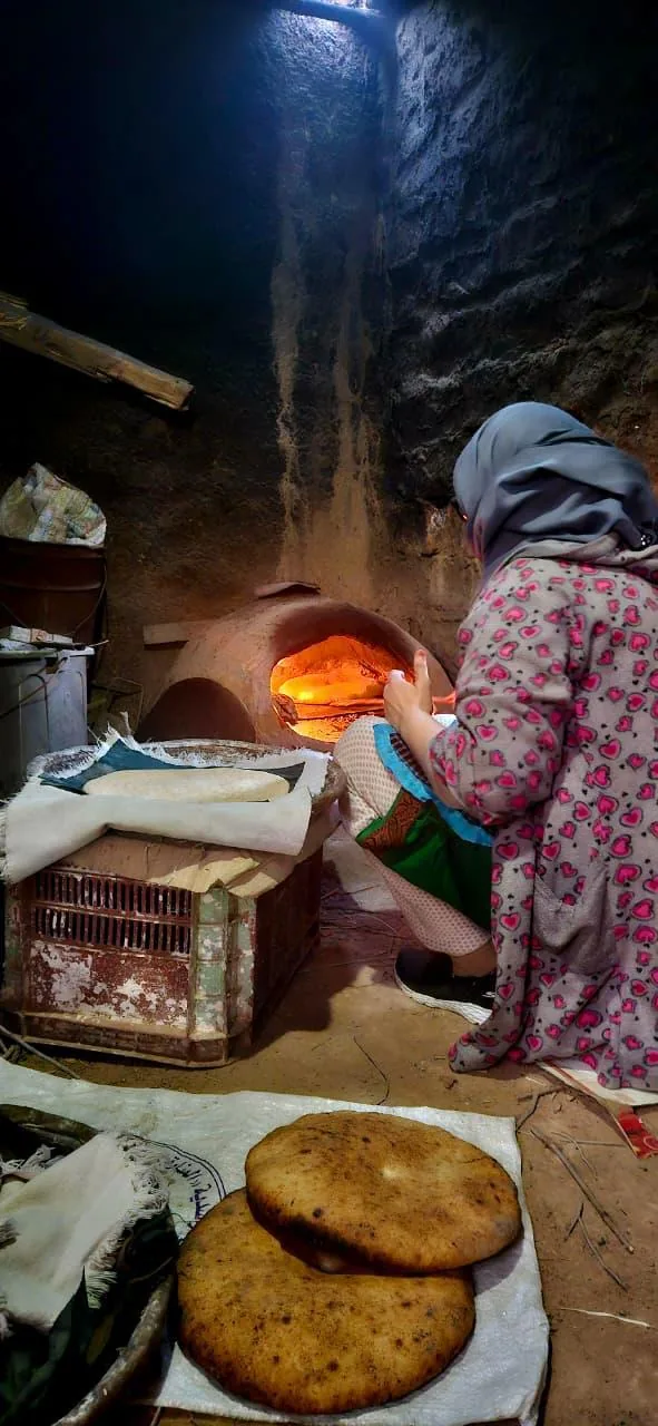 Mujer horneando pan tradicional en un horno de barro