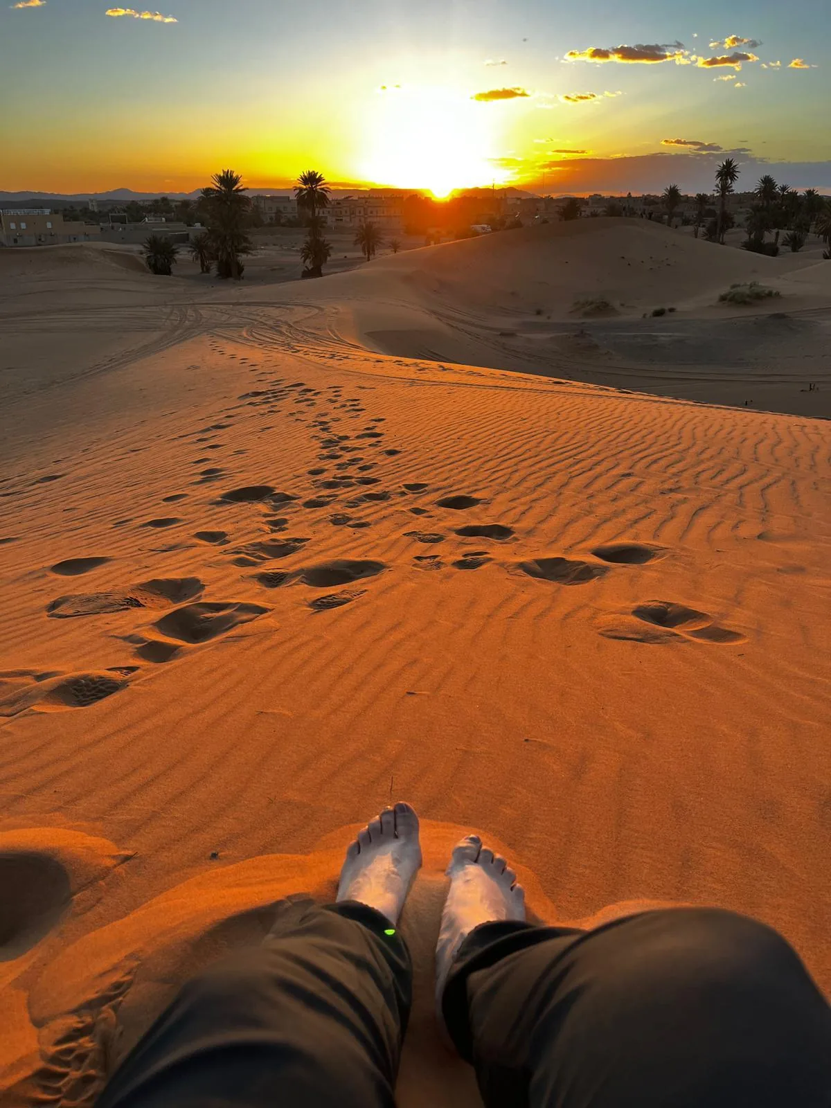 Vista en primera persona de unos pies sobre una duna al atardecer