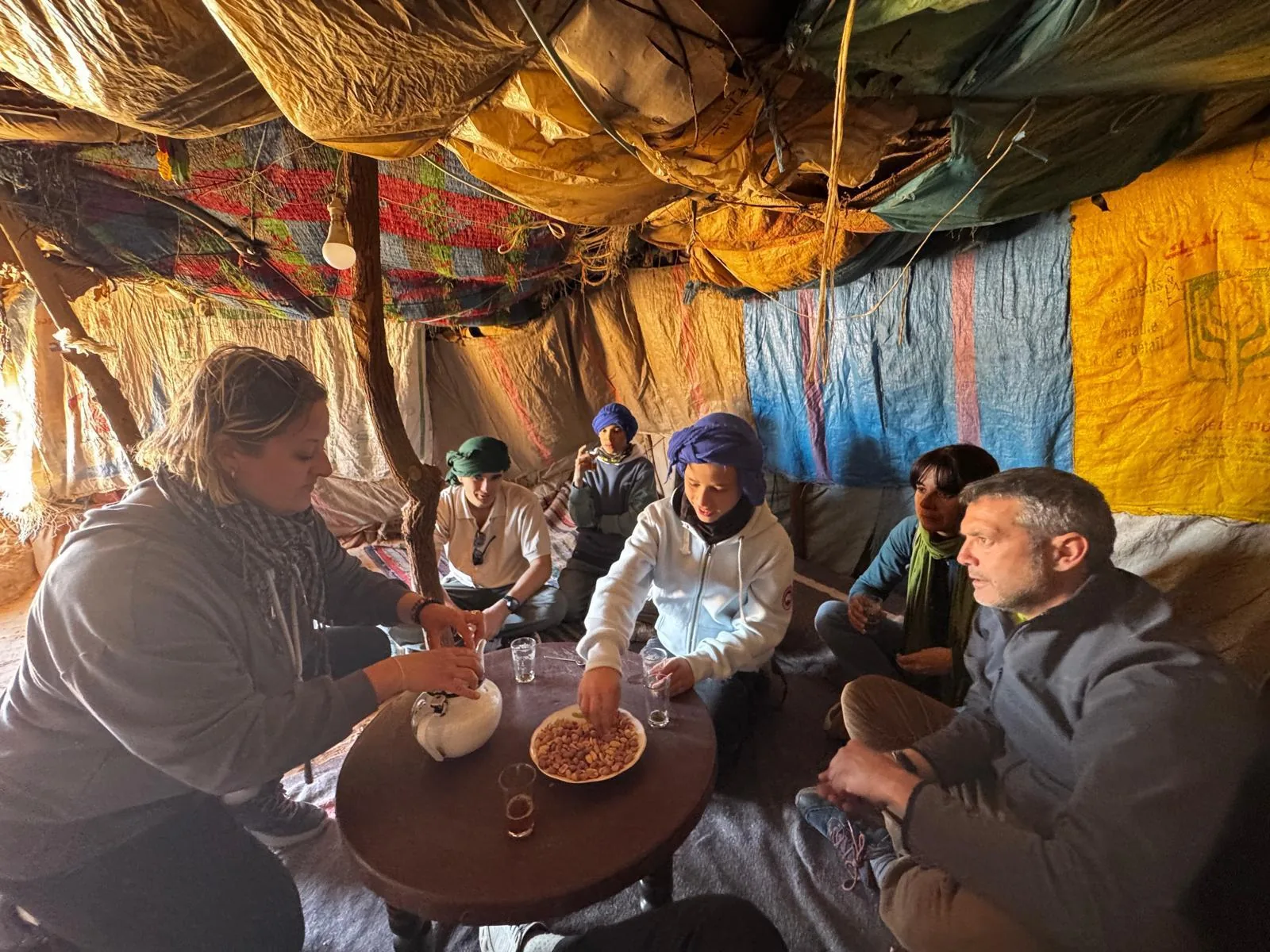 Grupo de viajeros compartiendo té bereber dentro de una jaima